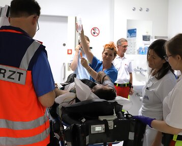 Ein Notarzt und mehrere medizinische Fachkräfte kümmern sich um einen Patienten auf einer Trage in einem Krankenhaus.