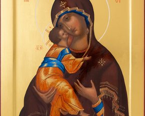 Die Ikone zeigt die Jungfrau Maria, die das Jesuskind hält. Maria trägt ein braunes Gewand mit goldenen Verzierungen, während das Kind in einem orangefarbenen und blauen Gewand gekleidet ist. Beide Figuren sind von einem goldenen Hintergrund umgeben.