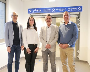 Vier Personen stehen in einem Flur vor einem Schild mit den Aufschriften „Atemtherapiezentrum“ und „Ambulantes OP-Zentrum“.
