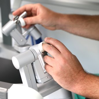 Hände bedienen präzise Steuerungen eines medizinischen Geräts in einer klinischen Umgebung.