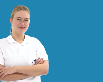Eine lächelnde Frau mit Brille trägt ein weißes Polohemd und steht mit verschränkten Armen vor einem blauen Hintergrund.
