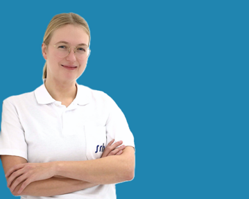 Eine lächelnde Frau mit Brille trägt ein weißes Polohemd und steht mit verschränkten Armen vor einem blauen Hintergrund.
