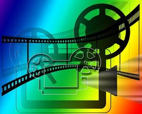 Filmrollen und ein Projektor vor einem bunten Hintergrund, symbolisierend die Film- und Medienproduktion.