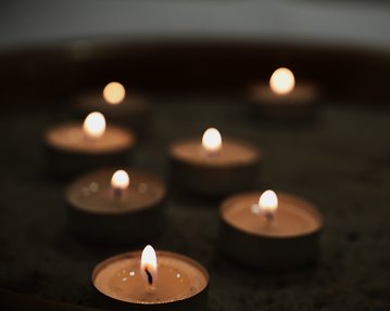 Teelichter brennen in einer flachen Schale, erzeugen warmes Licht und schaffen eine ruhige Atmosphäre.